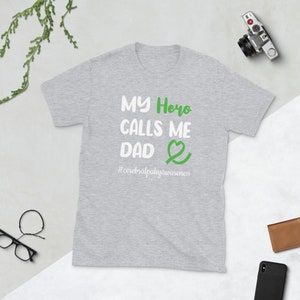 May include: Gray t-shirt with the text "My Hero Calls Me Dad" and a green ribbon with a heart. The text "#cerebralpalsyawareness" is below the ribbon.