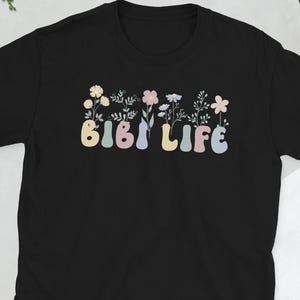 May include: Black t-shirt with a colorful graphic of flowers and the text "BIBI LIFE" in a retro font.