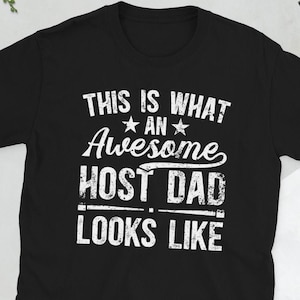 May include: Black t-shirt with white text that reads "This is what an awesome host dad looks like".