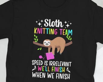 Op de afbeelding: Zwart T-shirt met een luiaard die op een tak breit. De tekst luidt "Sloth Knitting Team Speed is Irrelevant We'll Finish When We Finish".