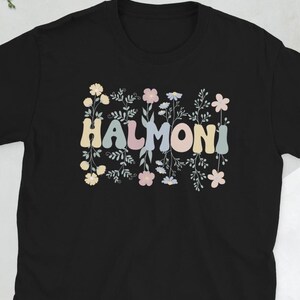 May include: Black t-shirt with a floral design and the word "HALMONI" in pastel colors.