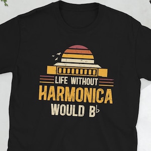 May include: Black t-shirt with a vintage-style graphic that says "Life Without Harmonica Would Be..." with a musical note at the end. The graphic features a sunset and a harmonica.