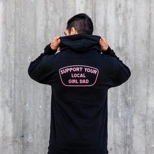 May include: A black hooded sweatshirt with a pink patch on the back that says "Support Your Local Girl Dad."