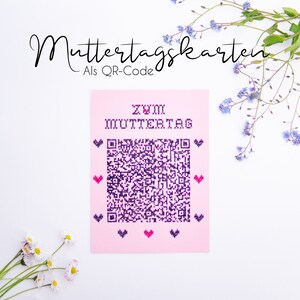 Könnte beinhalten: Eine rosa Karte mit einem violetten QR-Code und dem Text "Zum Muttertag" in weiß. Die Karte ist von weißen Blumen und blauen Vergissmeinnicht umgeben.