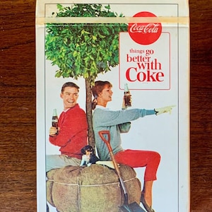 May include: A vintage Coca-Cola advert featuring a couple and a dog sitting on a bale of hay. The text reads "things go better with Coke".