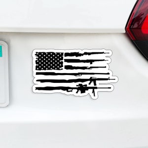 May include: A black and white sticker featuring a stylized American flag design. The stripes are replaced with silhouettes of various firearms. The upper left corner displays a field of white stars on a black background.