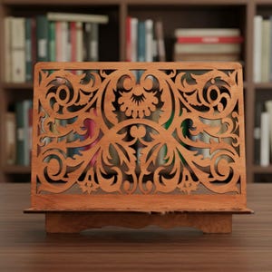 Pode incluir: Um suporte de livro de madeira com um design intrincado e vazado. O suporte &eacute; feito de madeira marrom clara e apresenta um padr&atilde;o decorativo floral e de rolagem. O suporte &eacute; projetado para segurar livros.