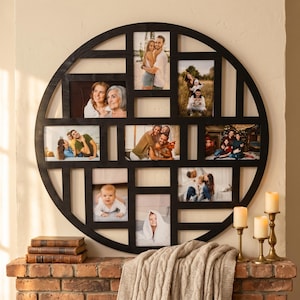 Puede incluir: Un marco de fotos circular grande de madera negra con múltiples aberturas rectangulares de varios tamaños. El marco contiene varias fotografías de familias e individuos, dispuestas en un patrón de cuadrícula dentro de la estructura circular.