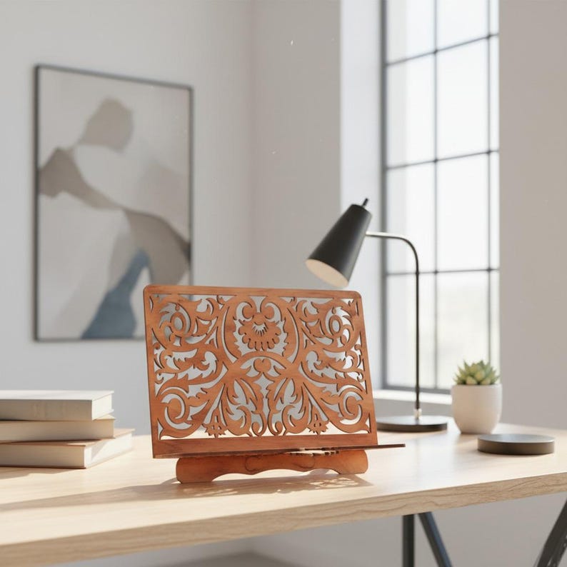 Pode incluir: Um suporte de livro de madeira com um intrincado design floral. O suporte &eacute; feito de madeira castanha clara e apresenta um padr&atilde;o decorativo recortado. Ele &eacute; projetado para segurar um livro e &eacute; colocado em uma mesa de madeira.