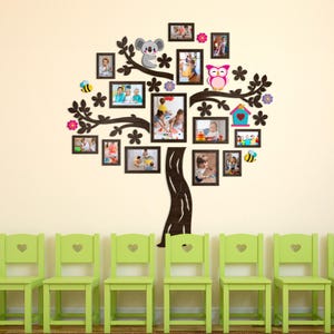 May include: A wall-mounted tree-shaped photo display with multiple black frames, decorated with a koala, owl, and flowers. Below, a row of green chairs with heart-shaped cutouts.