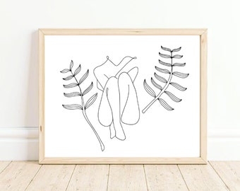 May include: Line art print of a person sitting with legs crossed, surrounded by two stylized plant branches. The print is in black and white and is framed in a light wood frame.