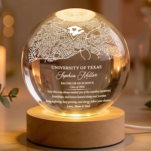 May include: A clear glass globe engraved with a map of the University of Texas, resting on a wooden base. The globe is illuminated from within, displaying the text "UNIVERSITY OF TEXAS Sophia Miller Bachelor of Science Class of 2026".