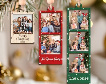 May include: Christmas ornaments with family photos. One wooden ornament has the text "Merry Christmas - 2026". Two red and green ornaments display family photos and names. Each ornament is rectangular and hangs from a string of wooden beads.