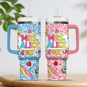 Peut inclure: Deux gobelets isothermes avec poign&eacute;es, un bleu et un rose, affichent le nom "MRS. ALICE" en lettres color&eacute;es. Les gobelets ont un couvercle blanc et une paille. Le design comprend des graphiques sur le th&egrave;me de l'&eacute;cole comme des pommes, des crayons et le mot "TEACH".