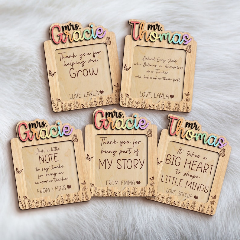 Op de afbeelding: Vier houten frames met gepersonaliseerde berichten voor leraren. De frames zijn versierd met vlinders en bloemen. De berichten zijn: "Bedankt dat je me hebt geholpen te groeien", "Achter elk kind dat in zichzelf gelooft, staat een leraar die in hen heeft geloofd", "Gewoon een klein berichtje om dank te zeggen voor het zijn van een geweldige leraar", en "Bedankt dat je deel uitmaakt van mijn verhaal".