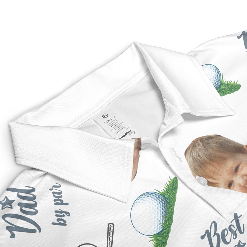 May include: White golf polo shirt with a personalized photo of a child's face, a golf ball, and the text "Dad by par" and "Best" on the shirt.