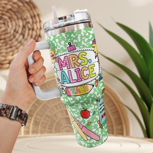 Peut inclure: Un gobelet en acier inoxydable avec une poign&eacute;e blanche et un couvercle transparent. Le gobelet est d&eacute;cor&eacute; d'un motif de papier de cahier vert et des mots "MRS. ALICE TEACH" en lettres color&eacute;es. Le gobelet pr&eacute;sente &eacute;galement des illustrations sur le th&egrave;me de l'&eacute;cole.