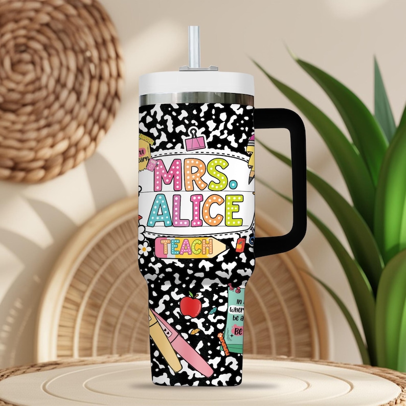 Peut inclure: Un gobelet isotherme blanc et argent&eacute; avec une poign&eacute;e et une paille noires. Le gobelet pr&eacute;sente un motif de cahier d'&eacute;colier noir et blanc avec le texte "MRS. ALICE TEACH" en lettres color&eacute;es. Des illustrations sur le th&egrave;me de l'&eacute;cole sont &eacute;galement pr&eacute;sentes.