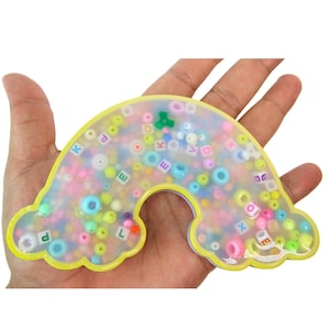 May include: A yellow rainbow-shaped resin tray filled with colorful beads and letter beads. The tray is approximately 6 inches wide and 4 inches tall.