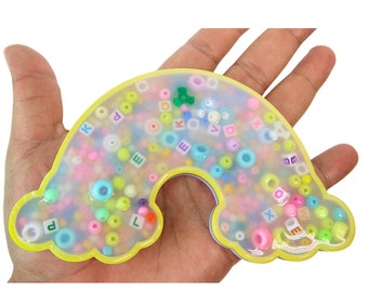 May include: A yellow rainbow-shaped resin tray filled with colorful beads and letter beads. The tray is approximately 6 inches wide and 4 inches tall.