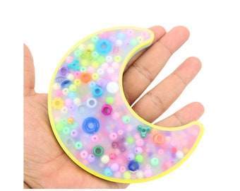 May include: A crescent moon-shaped resin tray filled with colorful beads. The tray is yellow and has a clear, iridescent finish.