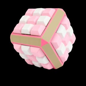 May include: A geometric puzzle toy with a cube shape. The cube is composed of pink and white blocks, with tan and pink accents. The toy is set against a black background.