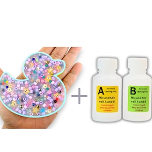 Könnte beinhalten: Eine transparente Plastikform in Form einer Ente, gefüllt mit bunten Perlen. Zwei Flaschen mit der Aufschrift A und B für das Gießen von Formen, mit Anweisungen zum Mischen und Rühren.