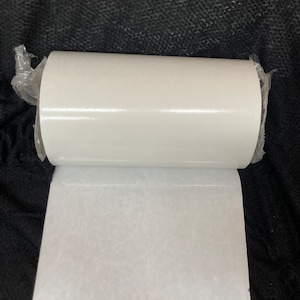 Puede incluir: Un rollo de papel blanco con una regla en la parte inferior. El papel está desenrollado, revelando una superficie texturizada. La regla muestra medidas en centímetros.