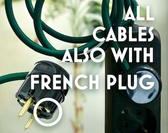 Op de afbeelding: Donkergroene elektrische kabel en stekkerdoos met een Franse stekker. De tekst op de afbeelding luidt "ALL CABLES ALSO WITH FRENCH PLUG". De kabel is opgerold en de stekkerdoos heeft meerdere stopcontacten.
