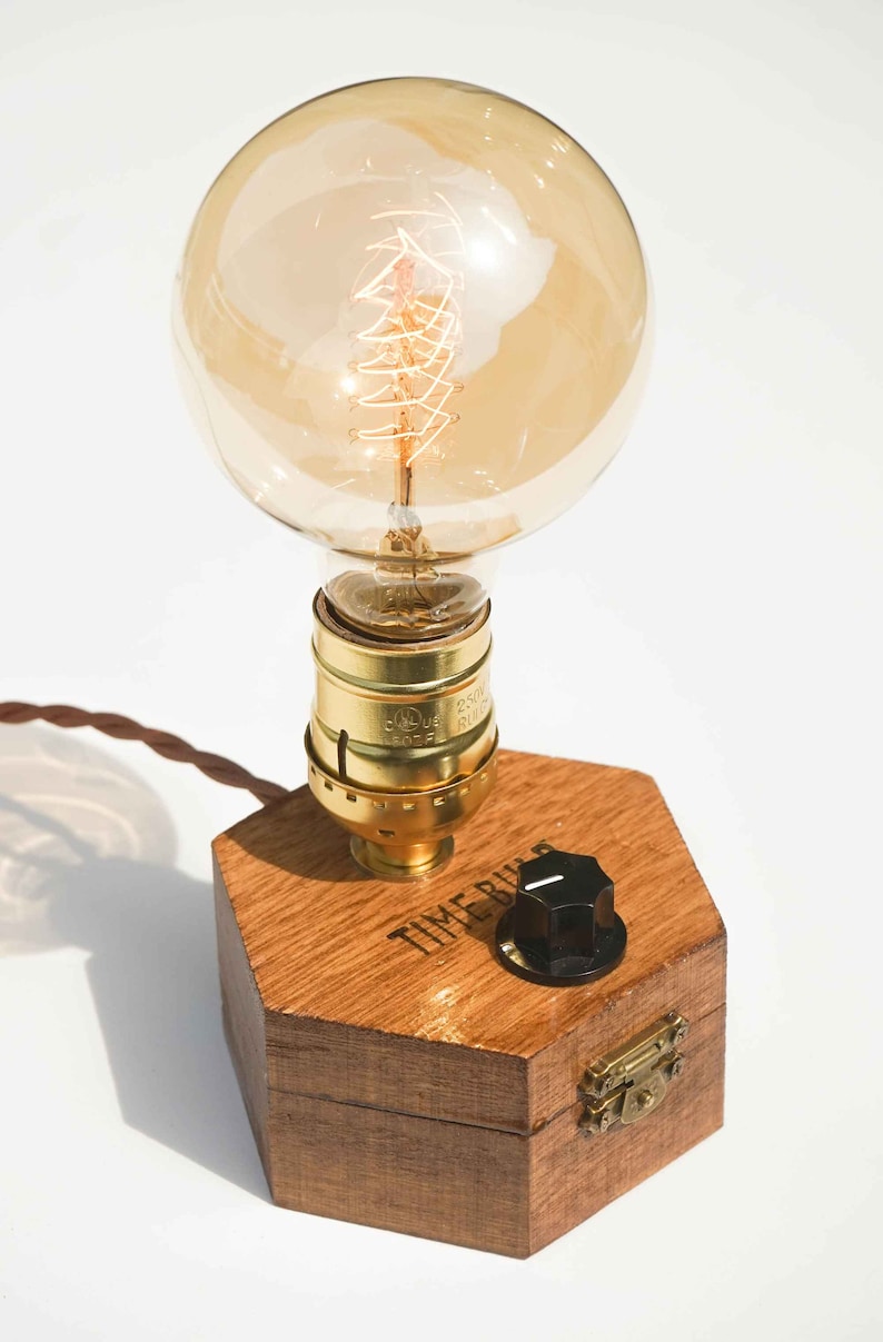 Dimmbare Tischlampe TIMEBULB Dim | Bakelit Knopf Dimmschalter Tischleuchte | Goldene Fassung Edison Birne | Minimalistisches Rustikales Industriedesign Holz Hexagon | Deko Geschenk. Available on Artigiano In Fiera 2024, Milano.