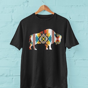 May include: Black t-shirt with a silhouette of a buffalo patterned with geometric shapes in orange, yellow, blue, and red.