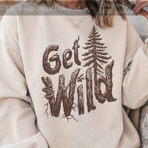 Peut inclure: Sweat-shirt crème avec l'inscription "Get Wild" en marron, dans une police rustique. Le motif comprend une illustration détaillée d'un pin et des lettres en bois stylisées, évoquant un thème inspiré de la nature. Le texte "PNG Image Digital Download" et "Designed by HBM Graphics" sont également visibles.