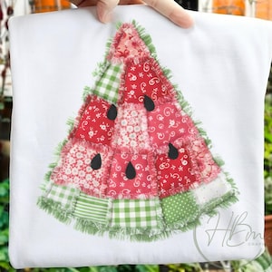 Puede incluir: Tela blanca con un diseño de rodaja de sandía en patchwork. La sandía presenta piezas de tela rojas, rosas y verdes con acentos de semillas negras. Los bordes están adornados con flecos verdes.