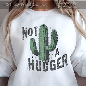 May include: White sweatshirt with a green cactus graphic and the text "Not a Hugger" in black with a distressed look.