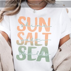 May include: White t-shirt with the words "SUN, SHINE, SALT, SEA, SHELLS" in orange and green block letters. The word "shine" is written in a cursive font. The shirt is a digital download.