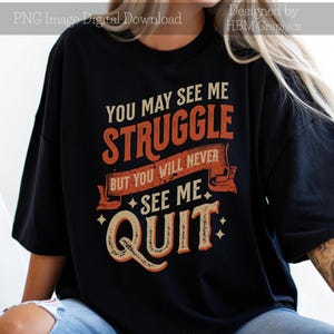 Puede incluir: Camiseta negra con una cita motivacional en texto naranja y blanco: "Puedes verme luchar, pero nunca me verás renunciar."