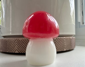 Może przedstawiać: Ceramiczna rzeźba grzyba w kolorze czerwonym i białym. Górna część grzyba jest jaskrawoczerwona, a dolna biała.