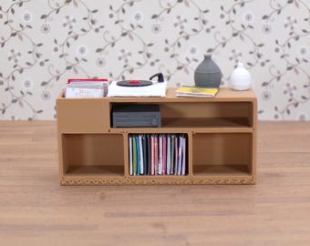 Può includere: Mobile da intrattenimento marrone in miniatura con giradischi, stereo e ripiani pieni di CD e libri. Due piccoli vasi sopra. L'unità è realizzata in materiale marrone chiaro ed è posta su una carta da parati floreale.