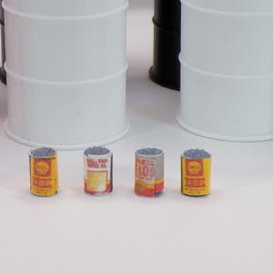 May include: Four small, gray metal oil cans with yellow and red labels. The labels read "Shell X100 Motor Oil" and "Shell X100".
