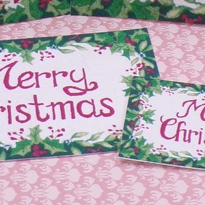 K&ouml;nnte beinhalten: Zwei rechteckige Weihnachts-Schilder mit gr&uuml;nem Stechpalmenrand und dem Text "Merry Christmas" in roten Buchstaben.