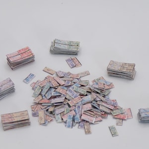 May include: A selection of small, rectangular paper pieces in pastel shades of pink, blue, and green. Some are stacked, others scattered on a white surface. The pieces have a textured, aged appearance, resembling miniature aged planks.