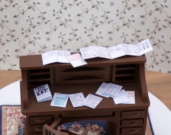 May include: A miniature brown wooden desk with multiple drawers and a top surface covered in stacks of papers. The papers are white with black text and appear to be tax forms.