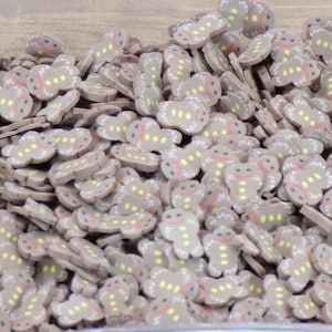 May include: A large quantity of brown gingerbread man-shaped sprinkles. The sprinkles have white icing details and yellow and red accents.