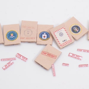 Peut inclure: Huit enveloppes en carton brun avec des &eacute;tiquettes d'avertissement rouges et blanches. Les &eacute;tiquettes indiquent "Top Secret", "Confidentiel", "Pour vos yeux seulement", "Ne pas photocopier", "F.B.I", "Classifi&eacute;", "Copie" et "S&eacute;curis&eacute;".