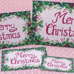 K&ouml;nnte beinhalten: Vier verschiedene Gr&ouml;&szlig;en von "Frohe Weihnachten"-Karten mit einem Rand aus Stechpalmen. Die Karten sind auf cremefarbenem Hintergrund mit roter Schrift gedruckt.