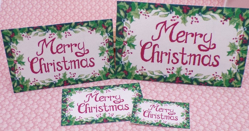 K&ouml;nnte beinhalten: Vier verschiedene Gr&ouml;&szlig;en von "Frohe Weihnachten"-Karten mit einem Rand aus Stechpalmen. Die Karten sind auf cremefarbenem Hintergrund mit roter Schrift gedruckt.