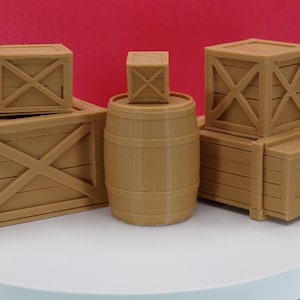 May include: A collection of miniature wooden crates and a barrel in various sizes. The crates have an X-shaped design on the sides. The items are a light brown color and are arranged on a white surface against a red background.
