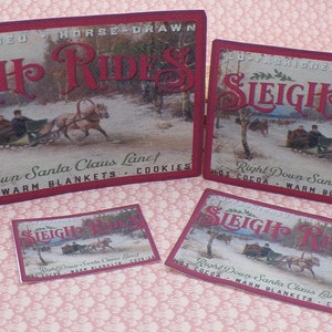 K&ouml;nnte beinhalten: Vier vintage rote und wei&szlig;e Schilder, die mit Pferden gezogene Schlittenfahrten bewerben. Die Schilder zeigen eine Winterszene mit einem von Pferden gezogenen Schlitten und dem Text "Old Fashioned Horse Drawn Sleigh Rides", "Right Down Santa Claus Lane! Hot Cocoa - Warm Blankets - Cookies".