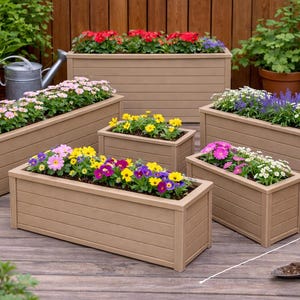 Könnte beinhalten: Mehrere rechteckige, hellbraune Holzpflanzkästen gefüllt mit bunten Blumen. Die Pflanzkästen sind unterschiedlich groß, einer misst 48 cm in der Höhe. Die Blumen umfassen rosa, lila, gelbe und weiße Blüten und schaffen eine lebendige Darstellung.