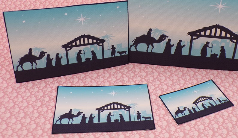 K&ouml;nnte beinhalten: Vier verschiedene Gr&ouml;&szlig;en von Weihnachtskarten mit einer Silhouette der Weihnachtsgeschichte mit einem Stern am Himmel. Die Karten sind auf blauem und wei&szlig;em Papier gedruckt.